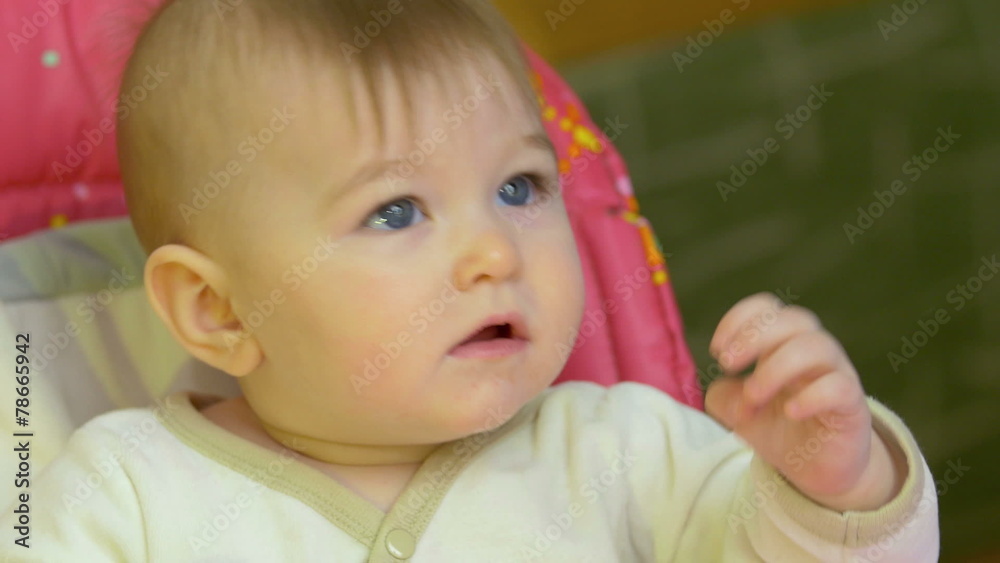 The baby sits on the chair, look forward and smile The baby sits on the chair, look forward and smile