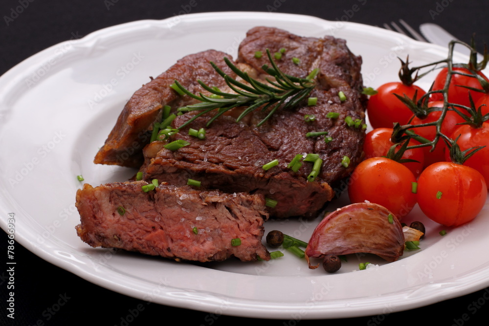 Rib eye steak with garlic, cherry tomatoes, herbs