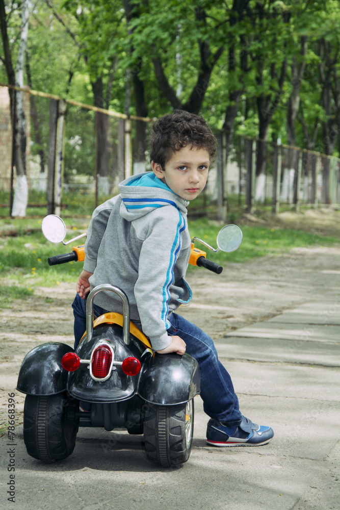 Spring on the street a little boy sitting on a motorcycle. Spring on the street a little boy sitting on a motorcycle.