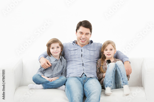 Family sitting on sofa smiling at camera on white background