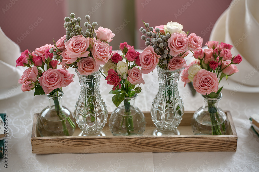 Fototapeta premium Five bouquets of roses on a festive wedding table in the restaur