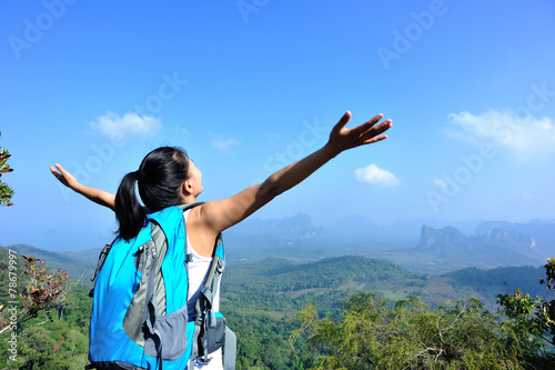 young woman hiker cheering open arms at mountain peak