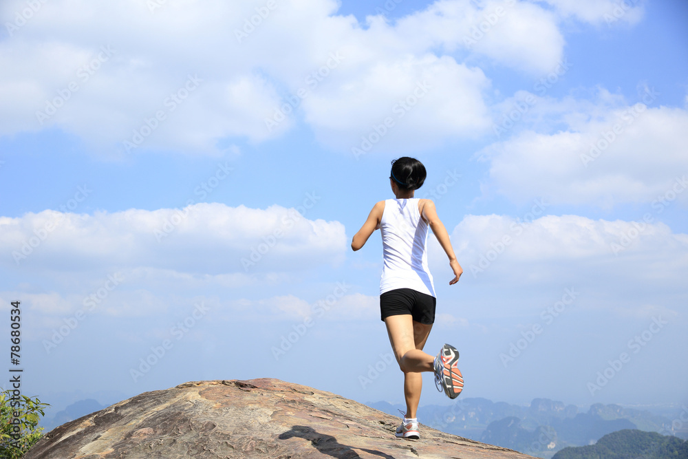 young asian woman running on mountain peak cliff young asian woman running on mountain peak cliff