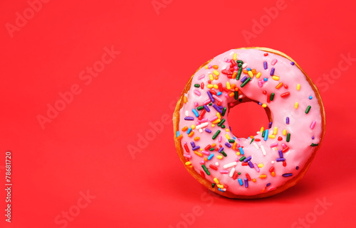Donut with sprinkles over red background