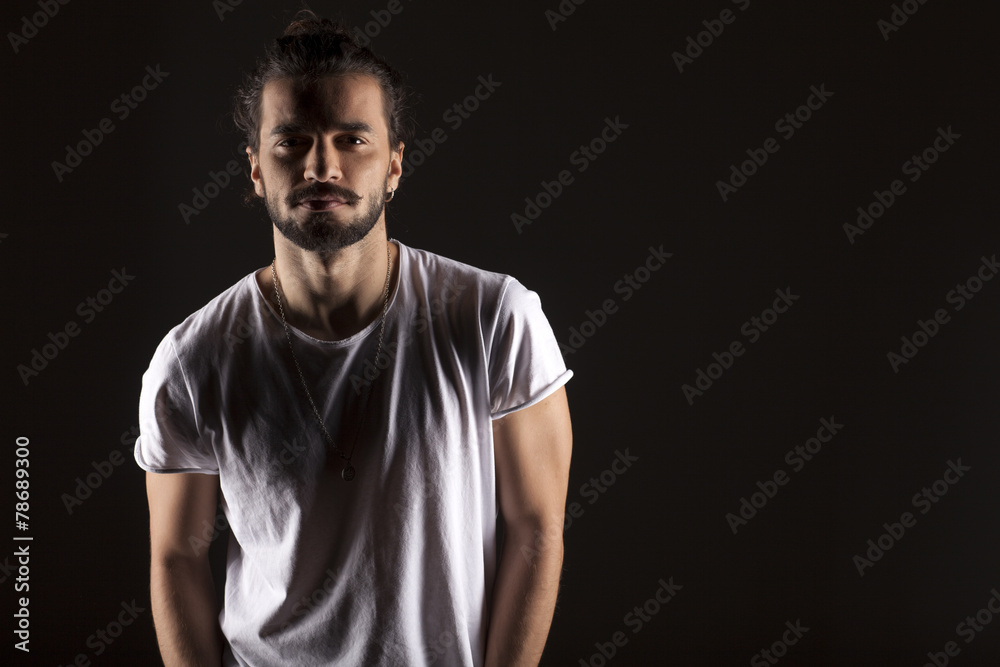 handsome young man with a beard on dark background