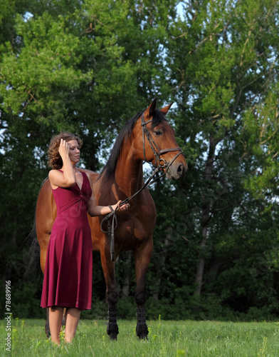 Attractive and shapely redhead woman with horse