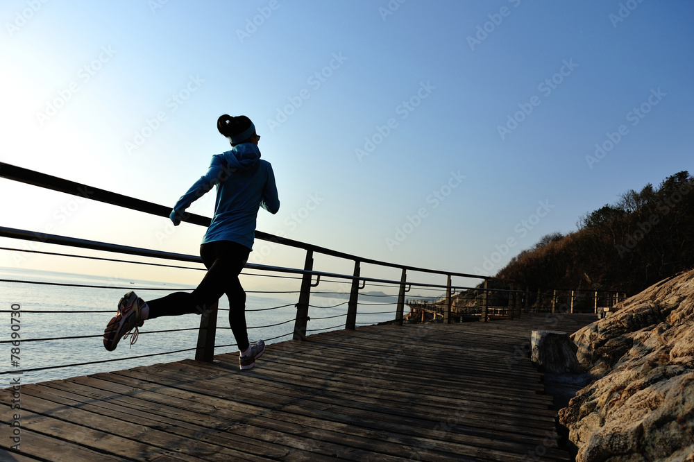 young fitness woman running on seaside boardwalk