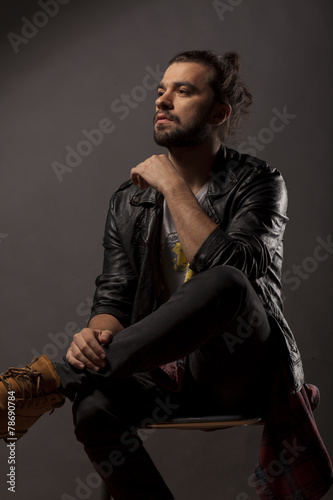 young man with beard and bun in black leather jacket photo