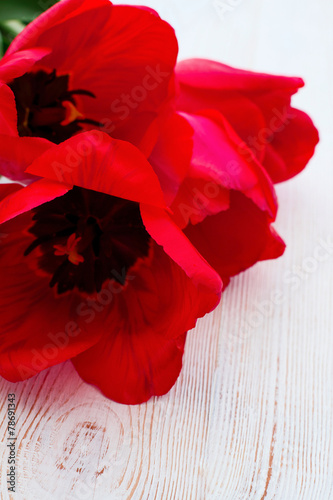 Fototapeta Naklejka Na Ścianę i Meble -  Macro bouquet of red tulips on wooden background. Selective focus