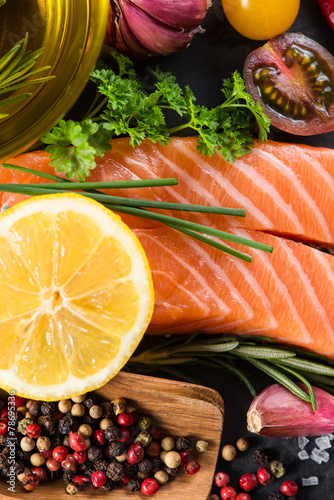 Portion of fresh salmon and herbs on black background photo