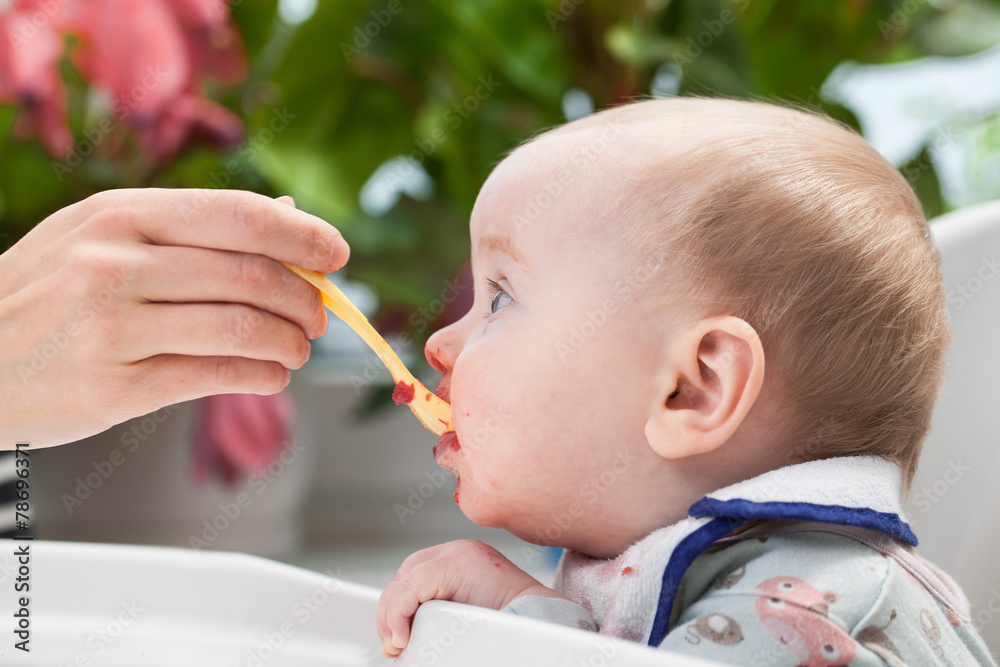 Mum feeds the baby boy from a spoon Mum feeds the baby boy from a spoon