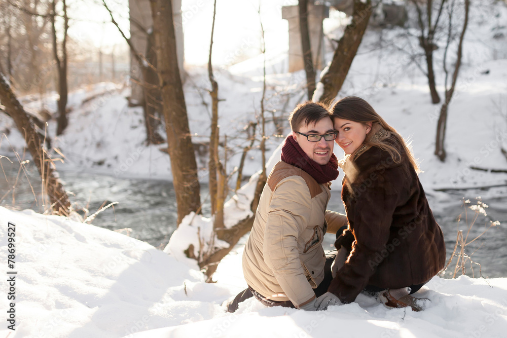 Fototapeta premium Cheerful couple in a pine forest in winter