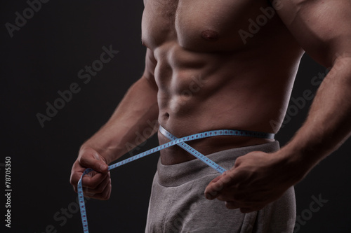 man measuring his waist with a tape measure