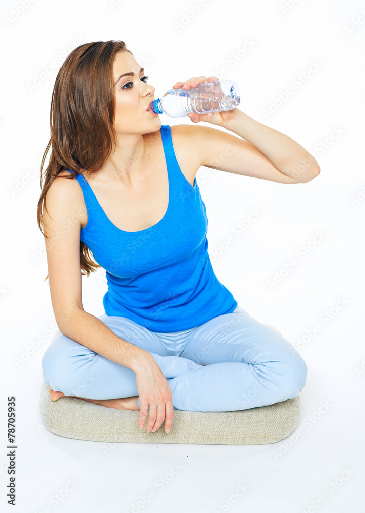 Young woman drinking water from bottle, sitting on a floor in y Young woman drinking water from bottle, sitting on a floor in y