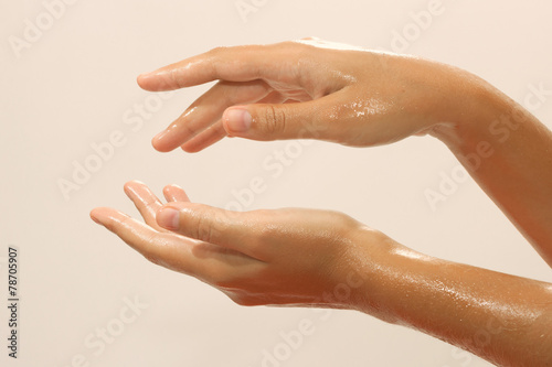 Close-up of female hands in oil on beige background