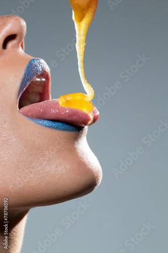 Woman dripping honey on her tongue