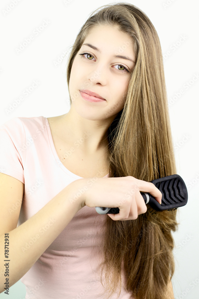 Fototapeta premium Teenager smiling while brushing long hair in studio