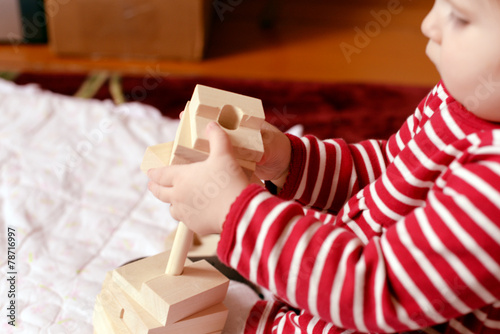Baby girl playing with a simple wooden toy