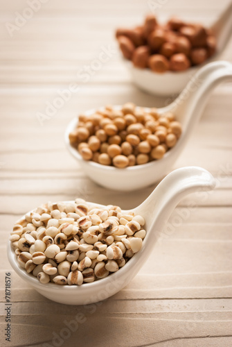 Different kinds of bean seeds, lentil, peas in dish on wooden ta