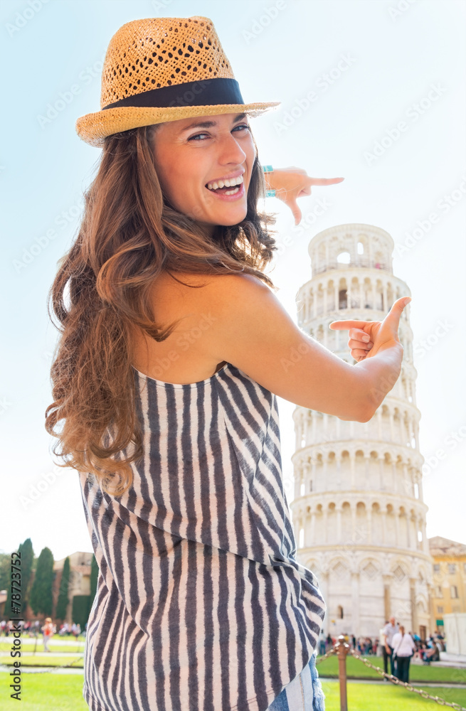 Happy young woman framing leaning tower of pisa, tuscany, italy