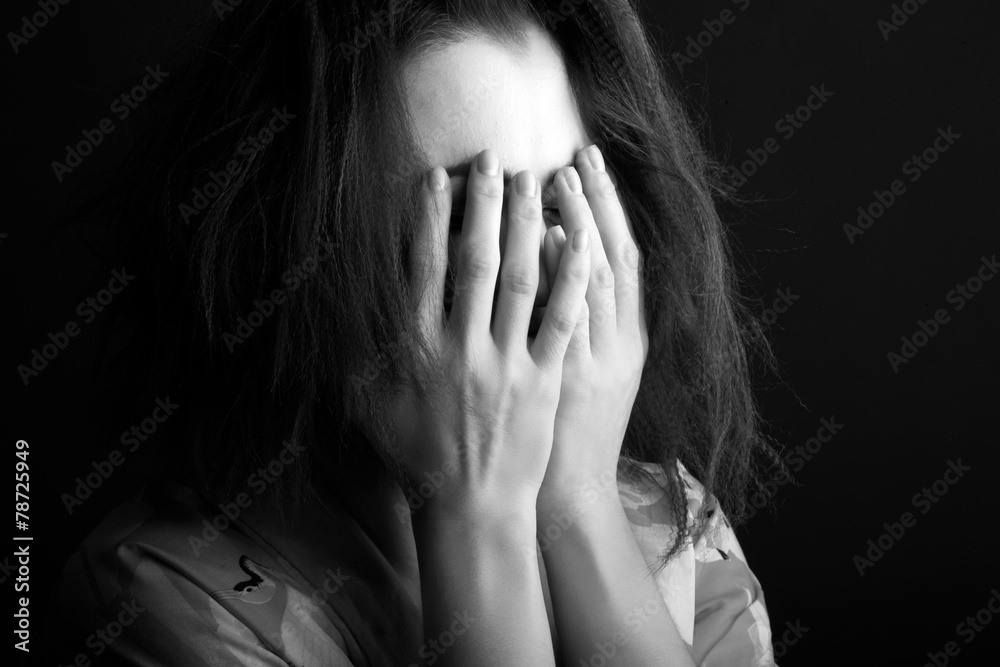 Fototapeta premium Woman hiding her face in hands, monochrome