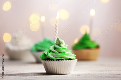 Delicious birthday cupcakes on table on light background