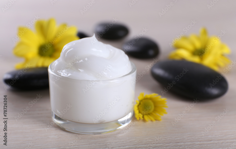 Cosmetic cream with flowers and spa stones on wooden background Cosmetic cream with flowers and spa stones on wooden background
