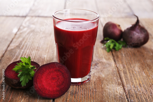 Glass of beet juice with beets on wooden table close up