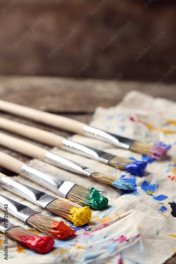 Obraz premium Brushes with colorful paints on dirty cloth
