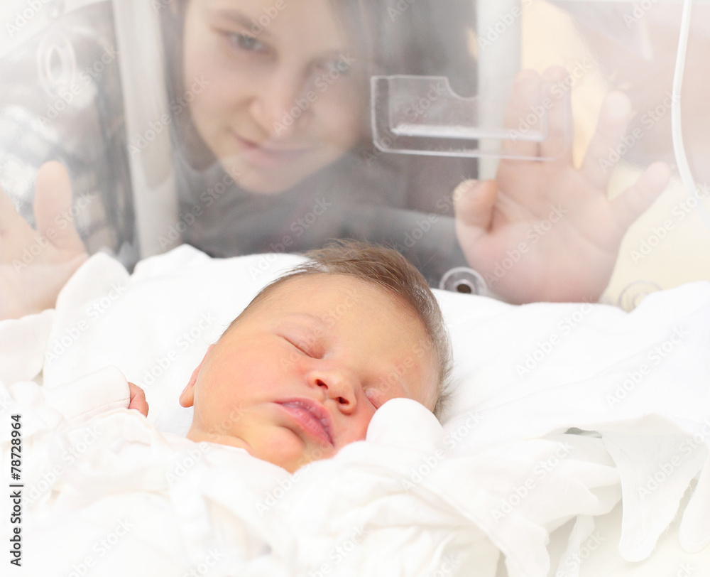 Baby girl sleeping in a incubator. Her mother looking at. Baby girl sleeping in a incubator. Her mother looking at.