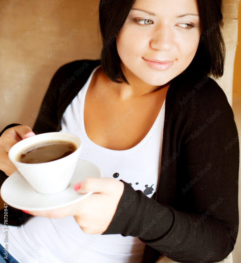 young woman sitting in a cafe drinking coffee