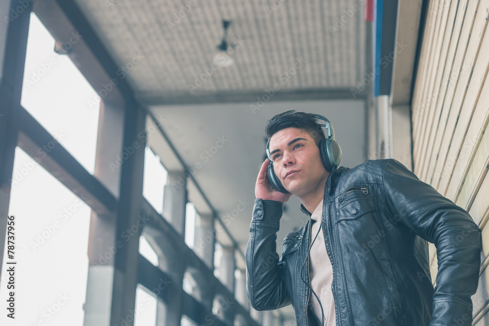 Young handsome man with headphones posing in the city streets Young handsome man with headphones posing in the city streets