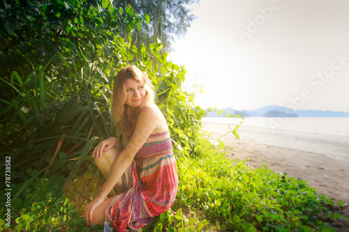 blonde girl in long dress  on grass near beach © SlavaStock