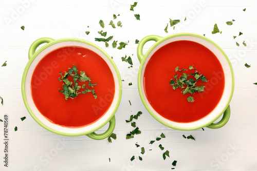 Classic tomato soup with parsley on white wooden background