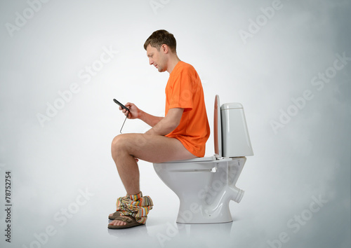 Man with smartphone sitting on the toilet