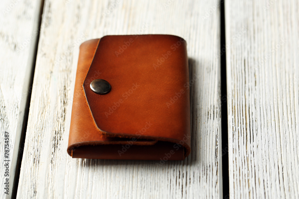 Hand made leather man wallet on white wooden background Hand made leather man wallet on white wooden background