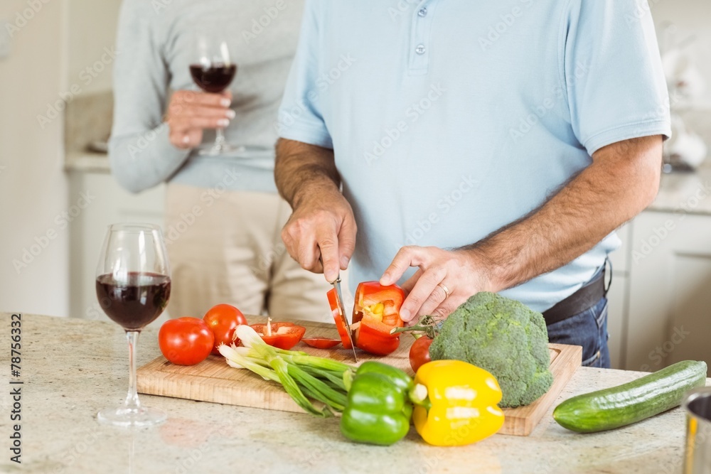 Mature couple having red wine while making dinner