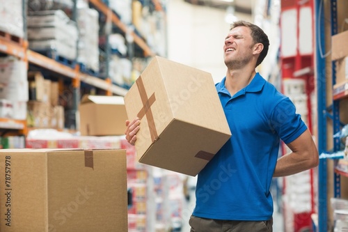 Worker with backache while lifting box in warehouse photo