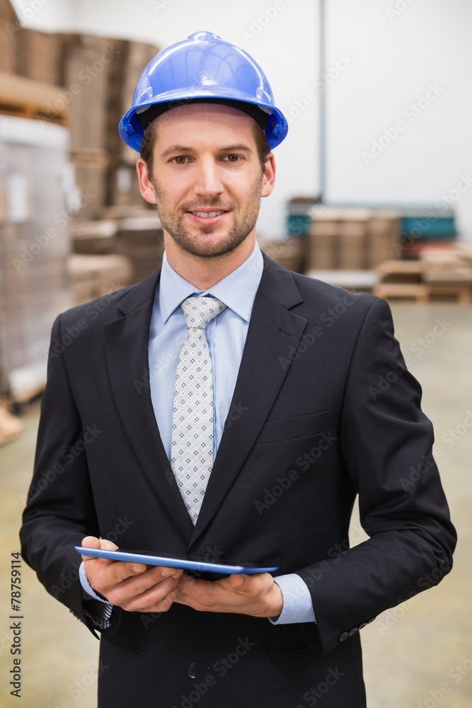 Warehouse manager wearing hard hat using tablet Warehouse manager wearing hard hat using tablet