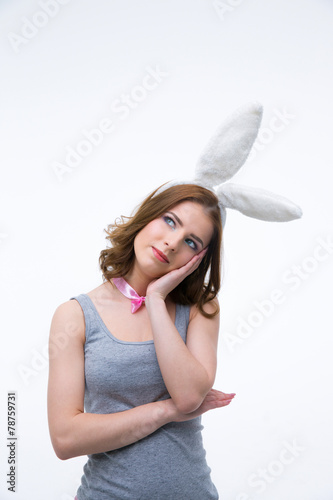 Pensive woman in rabbit ears looking up at copyspace