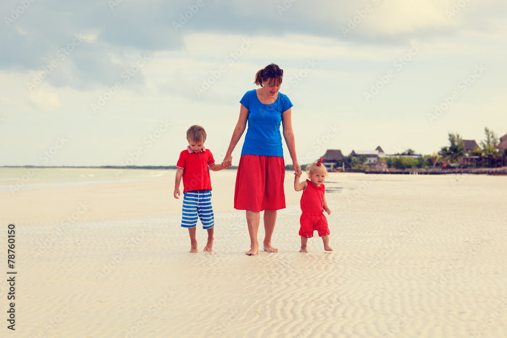 mother with two kids walking on beach