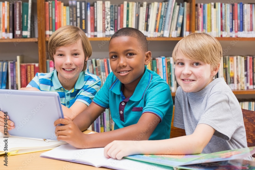 Fototapeta premium Cute pupils using tablet computer in library