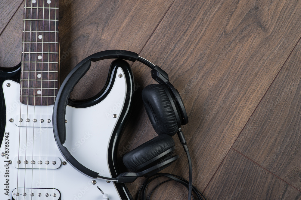 Electric guitar with headphones on a brown wooden floor Electric guitar with headphones on a brown wooden floor
