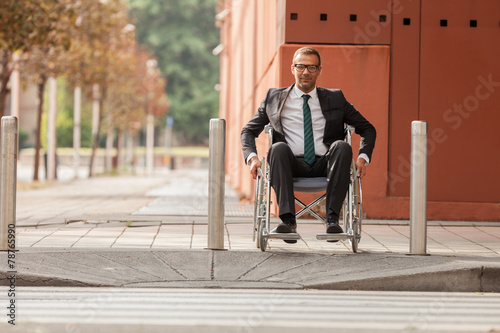 Businessman on wheelchair is trying to cross the road