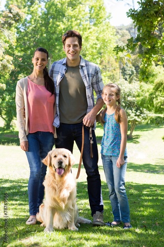 Happy family walking their dog in the park
