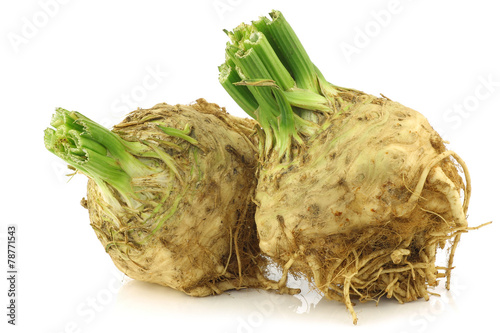 fresh celery roots with some foliage on a white background