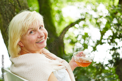 Alte Frau beim Tee trinken im Garten