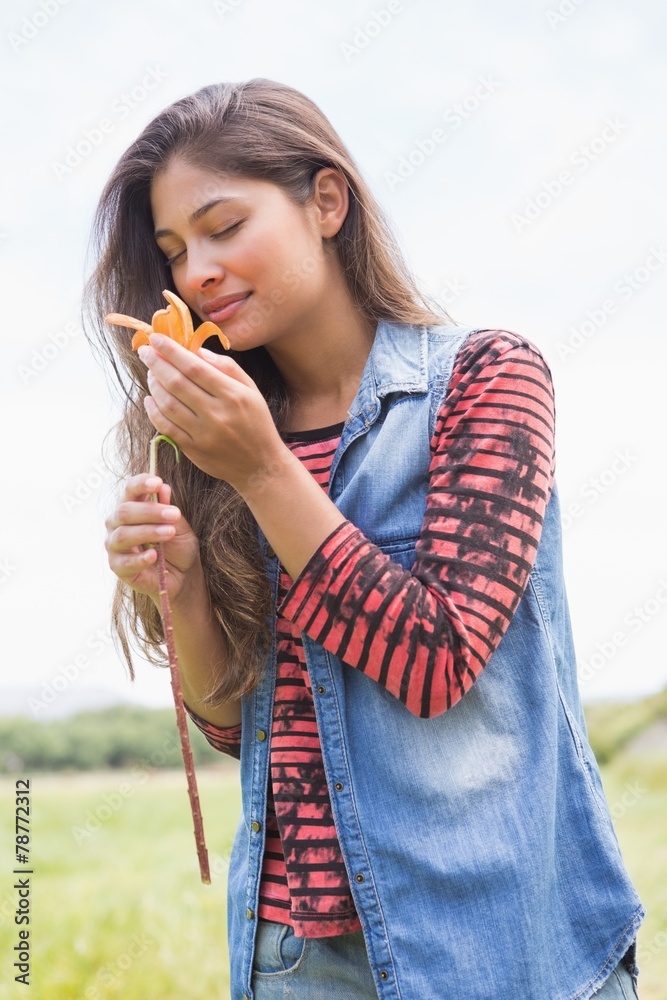 Fototapeta premium Pretty brunette smelling a flower
