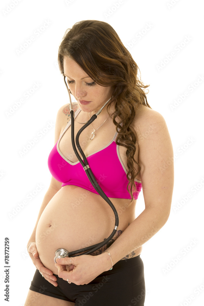 woman pregnant pink bra looking down at belly with stethoscope