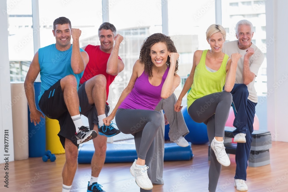 People performing aerobics exercise in gym class People performing aerobics exercise in gym class
